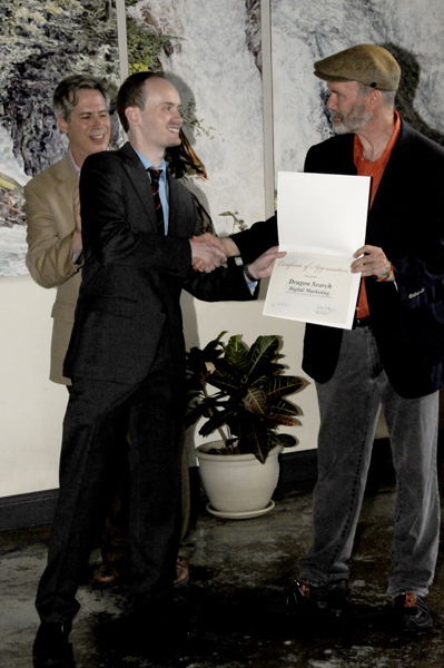 Tim Distel presenting a certificate of appreciation to Ric Dragon with Mayor Gallo in the back