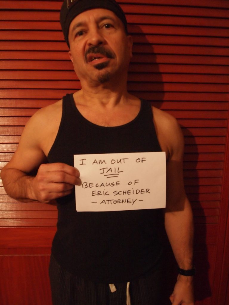 criminal-freed-from-jail Criminal holding sign "I am out of Jail because of Eric Scheider Attorney"