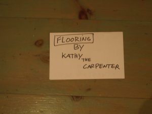 sign-giving-credit-for-wood-floor-carpentry Sign on floor reading "Flooring by Kathy the Carpenter"