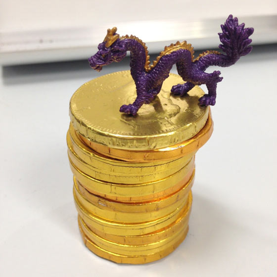 A stack of gold chocolate coins awarded to an intern; a purple dragon sits on top