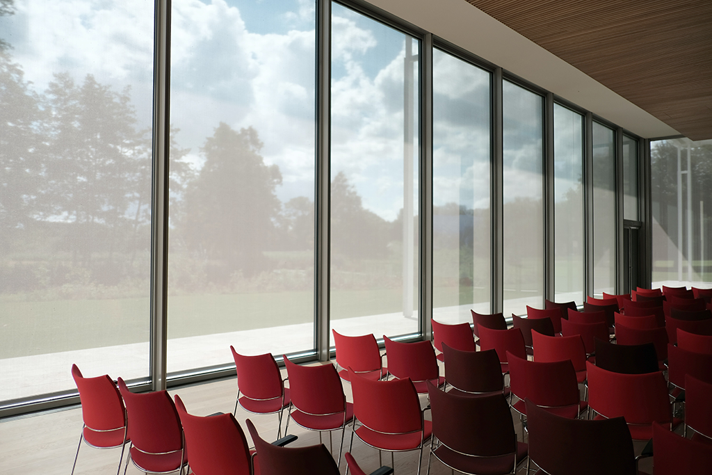 wide open conference room with floor to ceiling windows with red chairs
